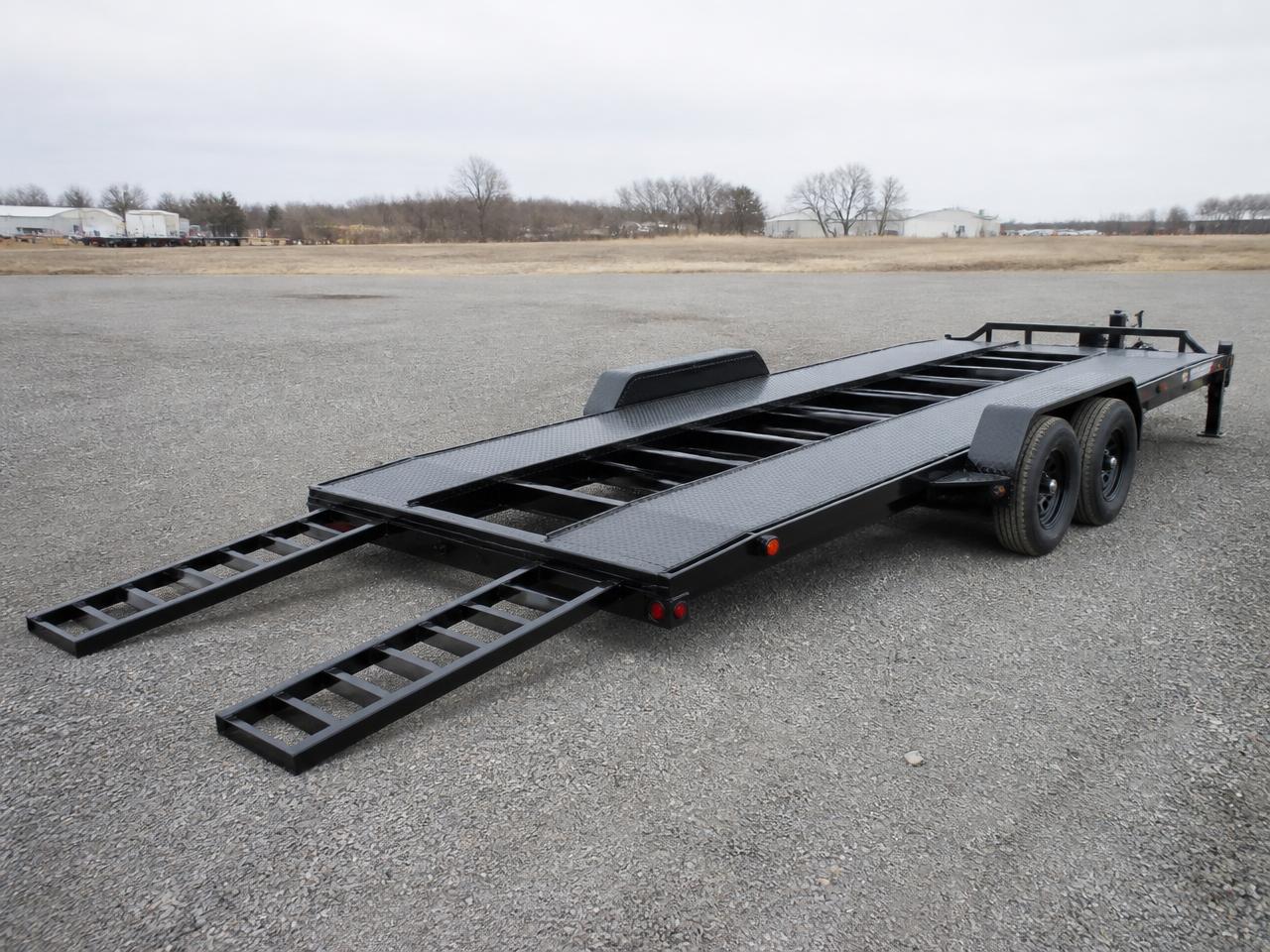 Steel open car hauler trailer with slide-out ramps extended on a gravel lot