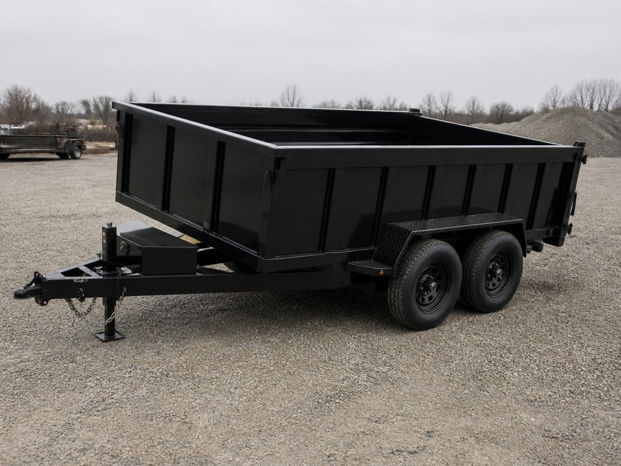 Heavy duty black hydraulic dump trailer with high sides parked on a gravel lot